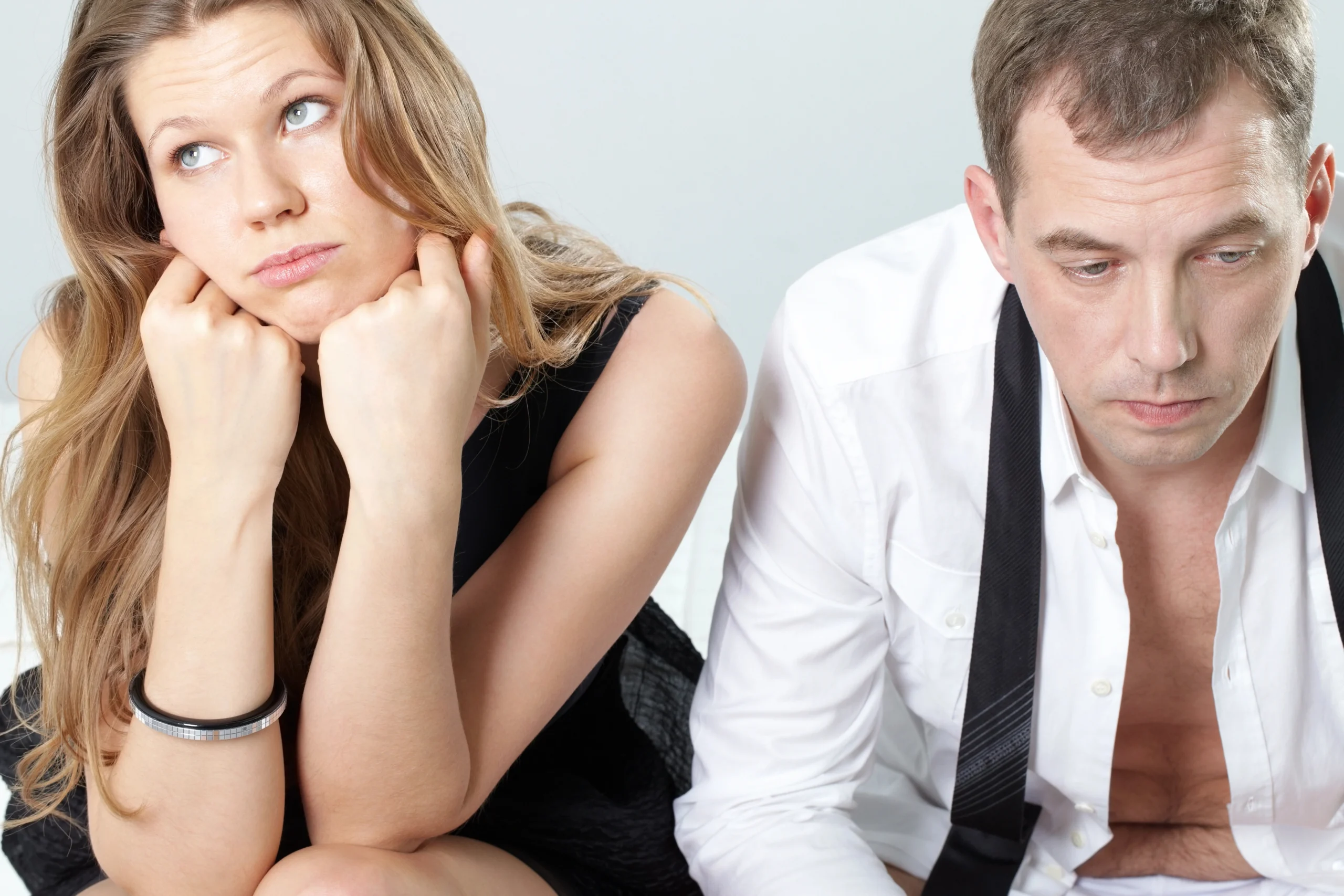ED. A woman looks up with her chin resting on her fists, while a man sits next to her looking down, both appearing unhappy or frustrated.