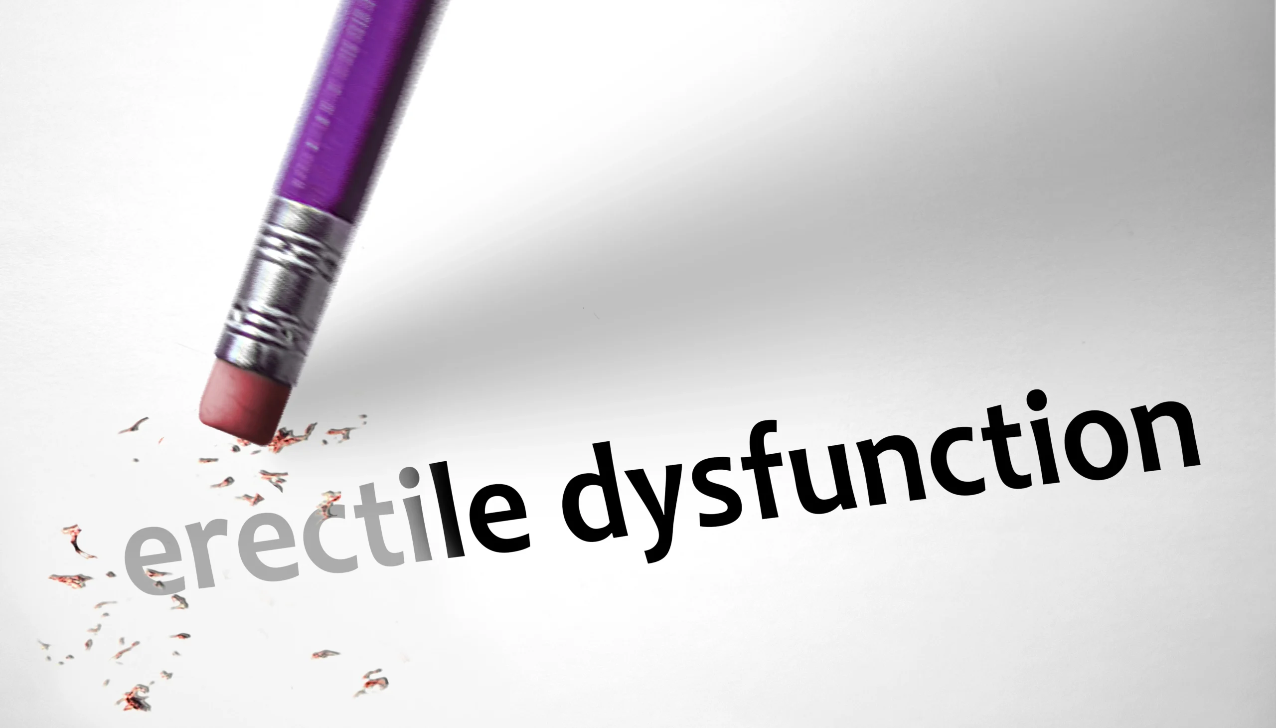 erectile dysfunction. A pencil eraser is erasing the word "erectile" from the phrase "erectile dysfunction" written on white paper.
