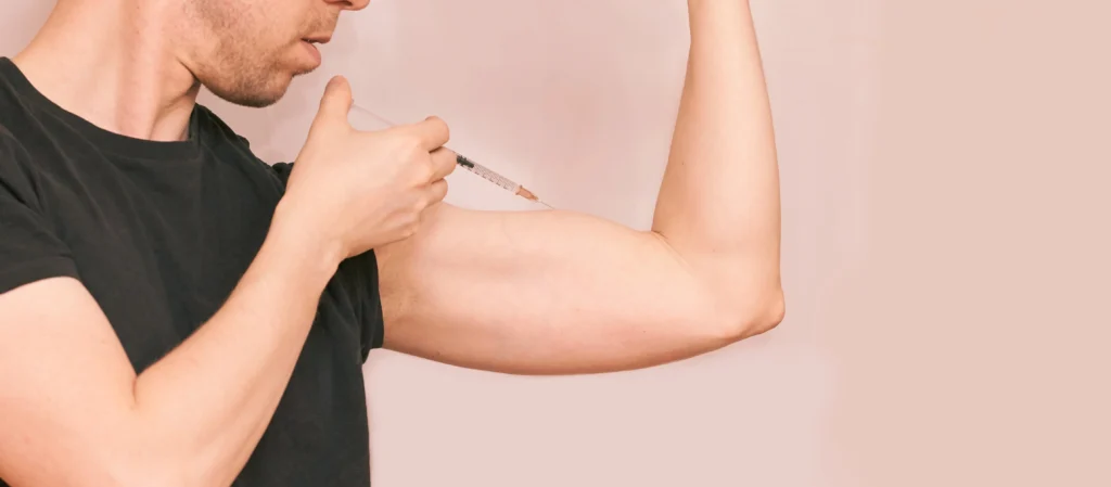 Testosterone levels. A person is injecting a syringe into their upper arm while flexing their bicep.