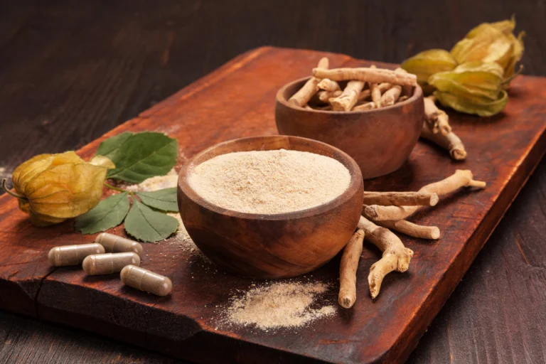 Ashwagandha. Wooden bowls with ashwagandha powder and roots on a wooden board, accompanied by ashwagandha capsules and leaves.